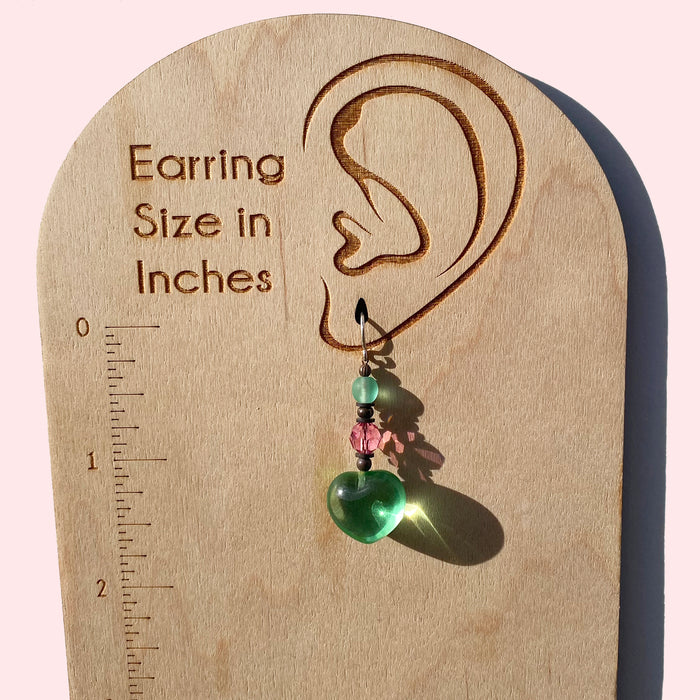 Peridot heart dangle earrings from Owen Glass Collection featuring vibrant green gemstones and silver hooks.