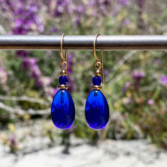 Cobalt glass and gold earrings from Owen Glass Collection featuring raindrop-shaped design with hanging glass and gold accents.