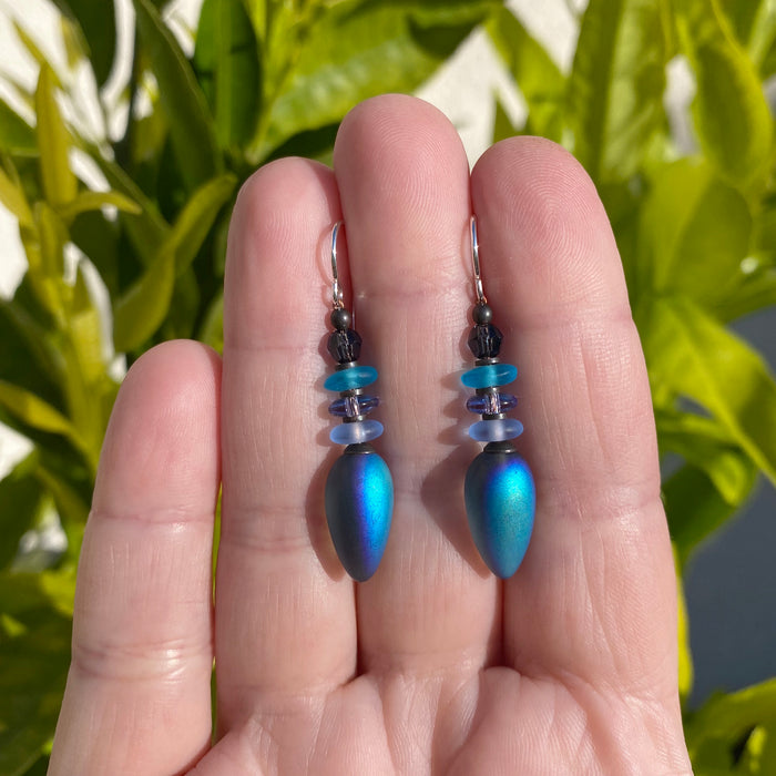Iridescent blue dangle earrings from Owen Glass Collection, featuring sleek, reflective design and elegant hanging style.