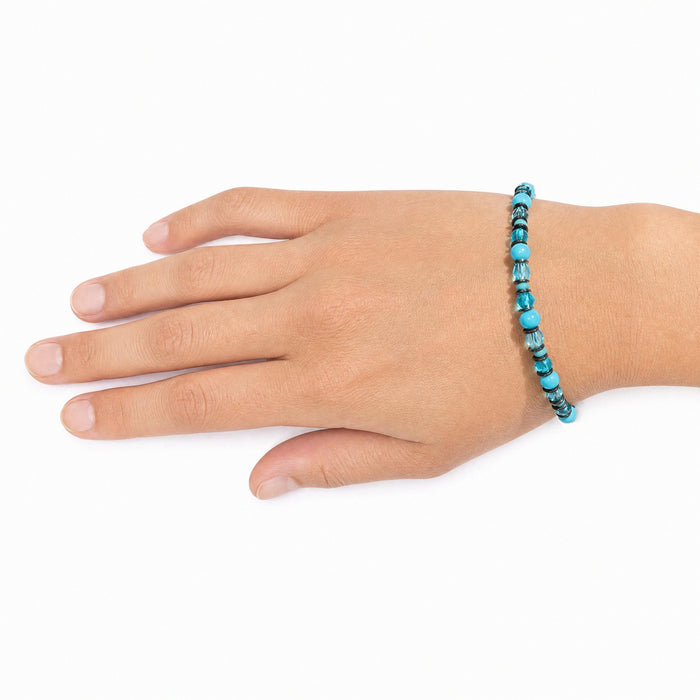 A beaded bracelet with turquoise blue and black beads worn on a person's wrist, shown against a plain white background.